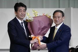Thủ tướng Nhật Bản sắp mãn nhiệm Shinzo Abe (trái) chúc mừng tân Chủ tịch đảng Dân chủ Tự do (LDP) cầm quyền vừa đắc cử Yoshihide Suga tại Tokyo ngày 14/9/2020. (Ảnh: TTXVN phát)