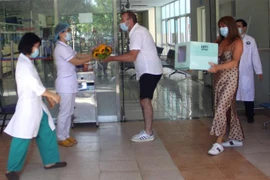 Hai vợ chồng bệnh nhân thứ 57 tặng hoa và quà cho đội ngũ y, bác sỹ Bệnh viện đa khoa Trung ương Quảng Nam. (Ảnh: Trịnh Bang Nhiệm/TTXVN)
