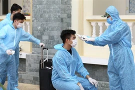 Đo kiểm tra thân nhiệt và làm thủ tục tiếp nhận hành khách về từ Đà Nẵng tại khu cách ly tập trung Trường quân sự Bộ Tư lệnh Thủ đô. (Ảnh: Minh Quyết/TTXVN)