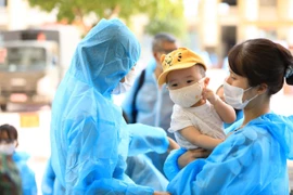 Một gia đình chờ làm thủ tục tại khu cách ly tập trung Trường quân sự Bộ Tư lệnh Thủ đô. (Ảnh: Thành Đạt/TTXVN)