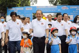 Phó Thủ tướng Thường trực Chính phủ Trương Hòa Bình cùng lãnh đạo các bộ, ngành Trung ương và Thành phố Hồ Chí Minh, các em học sinh tiểu học đi bộ vận động toàn dân 'Đội mũ bảo hiểm cho trẻ em' trên đường Lê Duẩn, quận 1, TP.HCM. (Ảnh: Thanh Vũ/TTXVN)