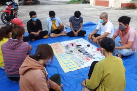 Các đối tượng tham gia đánh bạc bị bắt giữ cùng tang vật. (Ảnh: Thanh Tân/TTXVN)