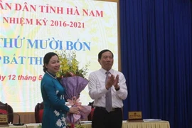 Ông Phạm Sỹ Lợi, Chủ tịch HĐND tỉnh Hà Nam tặng hoa chúc mừng bà Đinh Thị Lụa. (Ảnh: Thanh Tuấn/TTXVN)