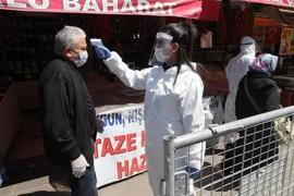 Nhân viên y tế kiểm tra thân nhiệt người dân tại một khu chợ ở Ankara, Thổ Nhĩ Kỳ nhằm ngăn chặn sự lây lan của dịch COVID-19 ngày 17/4/2020. (Ảnh: THX/TTXVN)