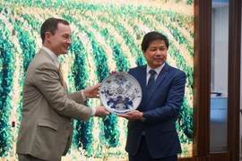 Thứ trưởng Lê Quốc Doanh tặng quà lưu niệm cho đại diện một hiệp hội ngành hàng của Mỹ. (Ảnh: Đặng Huyền/Vietnam+)