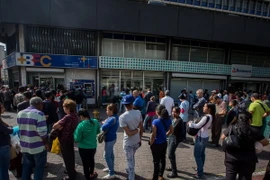 Người dân Venezuela xếp hàng chờ giao dịch bên ngoài Ngân hàng Trung ương ở Caracas. (Nguồn: EPA/TTXVN)