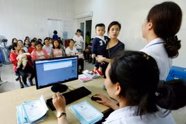 Nhân viên y tế làm thủ tục tiêm chủng cho trẻ tại Trung tâm Y tế Dự phòng Hà Nội. (Ảnh: Dương Ngọc/TTXVN)