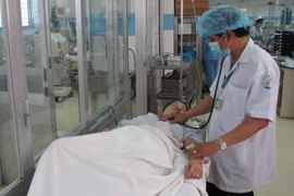 Bác sỹ bệnh viện Nhiệt đới TP. HCM thăm khám cho bệnh nhi bị sốt xuất huyết. (Ảnh: Phương Vy/TTXVN)