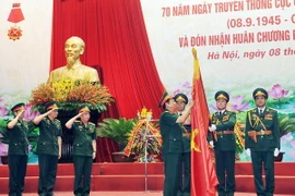 Thượng tướng Đỗ Bá Tỵ gắn Huân chương Bảo vệ Tổ quốc hạng Nhì lên Cờ truyền thống của Cục Quân lực. (Ảnh: Trọng Đức/TTXVN)