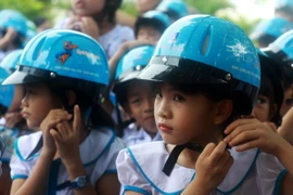Các em học sinh đội mũ bảo hiểm. (Ảnh: Sỹ Thắng/TTXVN)