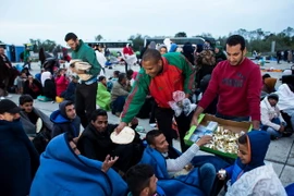 Nhân viên tình nguyện phân phát thực phẩm cho những người di cư đợi xe buýt để vào sâu trong lãnh thổ Áo tại Nickelsdorf khu vực biên giới Áo và Hungary ngày 5/9. (Nguồn: AFP/TTXVN)