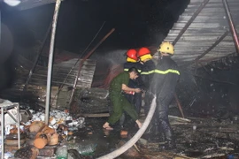 Lực lượng chức năng nỗ lực phun nước dập lửa tại hiện trường vụ cháy. (Ảnh: Tường Vi/TTXVN)