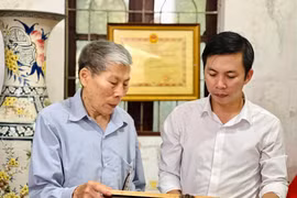 Ông Nguyễn Hữu Luyên cùng con trai ôn lại truyền thống vẻ vang của các liệt sỹ, Bà mẹ Việt Nam anh hùng trong gia đình. (Ảnh: PV/Vietnam+)