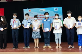 Đại diện Công đoàn BIDV trao tặng sổ tiết kiệm cho các em có hoàn cảnh mồ côi tại sự kiện. (Ảnh: Vietnam+)