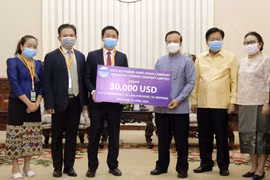 Ông Đinh Ngọc Diệp, Trưởng Đại diện Công ty CP điện Việt Lào (trái) và Phó Thủ tướng, Bộ trưởng Tài chính Lào Somdy Duangdy (Phải) tại lễ trao tiền ủng hộ. (Ảnh: PV/TTXVN)