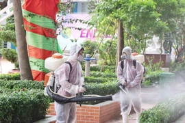 Nhân viên y tế phun thuốc khử khuẩn khu vực sân trường, cây cối, đảm bảo vệ sinh cho khuôn viên trường. (Ảnh: Thu Hương/TTXVN)