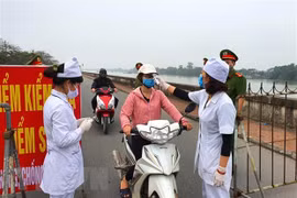 Đo thân nhiệt người qua lại khu đường đê ven sông Đào thành phố Nam Định. (Ảnh: Công Luật/TTXVN)