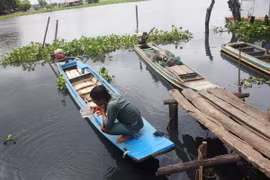 Người dân sống ven sông kiểm tra nguồn nước khi phát hiện mặt sông đã chuyển thành màu đen sẫm và kèm theo mùi hôi khó chịu. (Ảnh: Thanh Tân/TTXVN)