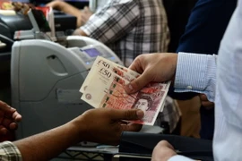Kiểm đồng bảng Anh tại một điểm giao dịch ngoại hối ở Singapore ngày 24/6. (Nguồn: AFP/TTXVN)