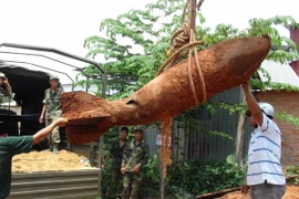 Chuyển quả bom lên xe chuyên dụng để đưa đi xử lý. (Ảnh: Đậu Tất Thành/TTXVN)