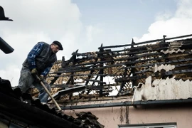 Người dân địa phương sửa chữa căn nhà bị đổ nát trong xung đột tại Donetsk ngày 6/4. (Nguồn: AFP/TTXVN)