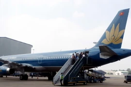 Hành khách lên máy bay của VNA tại sân bay quốc tế Tân Sơn Nhất. (Ảnh: Hoàng Hải/TTXVN)