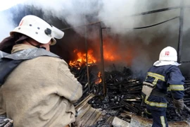Lính cứu hỏa dập lửa đám cháy khu chợ ở Donetsk sau vụ pháo kích trong xung đột. (Nguồn: AFP/TTXVN)