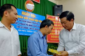 Ủy viên Bộ Chính trị, Bí thư Thành ủy Thành phố Hồ Chí Minh Đinh La Thăng tặng quà cho các gia đình chính sách khó khăn tại Khu phố 4, phường 7, quận 3. (Ảnh: Thế Anh/TTXVN)