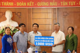 Đại sứ Nguyễn Mạnh Hùng đang tiếp nhận số tiền tượng trưng từ Đại diện câu lạc bộ Đồng hương Xi​eng Kho​ang. (Ảnh: Phạm Kiên/Vietnam+)