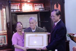 Ông Hà Anh Dân, (ngoài cùng bên phải) đang trao quyết định của Đảng Cộng sản Việt Nam tặng Huy hiệu 65 năm tuổi Đảng cho ông Trần Văn Mỹ. (Ảnh: Phạm Kiên/Vietnam+)