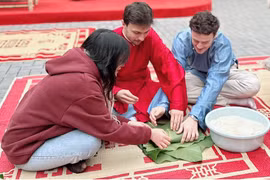 Sinh viên quốc tế hào hứng khi lần đầu tiên trải nghiệm gói bánh chưng. (Ảnh: PV/Vietnam+)