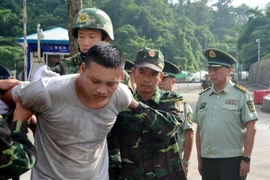 Các lực lượng chức năng Việt Nam nhận bàn giao đối tượng bị truy nã tại Cửa khẩu Quốc tế Hữu Nghị. (Ảnh: Thái Thuần/TTXVN)