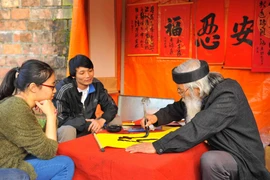 Các bạn trẻ mua chữ đầu năm để cả năm đón tài lộc, may mắn vào nhà. (Ảnh: Minh Đức/TTXVN)