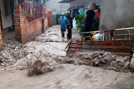 Nước chảy xiết kéo theo đất sỏi khiến việc đi lại của người dân gặp khó khăn. (Ảnh: Nguyễn Hoàng/TTXVN)