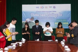 Các đại biểu nhắn tin ủng hộ Chương trình tại buổi lễ. (Ảnh: Quý Trung/TTXVN)