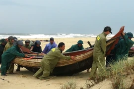 Lực lượng vũ trang Quảng Trị hỗ trợ người dân đưa thuyền vào bờ. (Ảnh: Thanh Thủy/TTXVN)