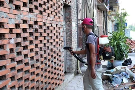 Nhân viên Trạm y tế dự phòng phường Tân Triều (huyện Thanh Trì) phun thuốc diệt muỗi đợt 2 cho các hộ gia đình trên địa bàn phường Tân Triều. (Ảnh: Quang Quyết/TTXVN)