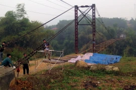 Công nhân Công ty trách nhiệm hữu hạn Thành Long đang khẩn trương sửa chữa cầu treo Bình Yên. (Ảnh Quang Đán/TTXVN)