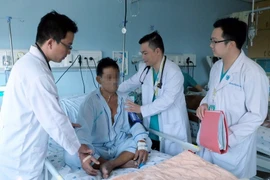 Các bác sỹ kiểm tra sức khỏe cho bệnh nhân B.H.B. (Ảnh: Phương Vy/TTXVN)
