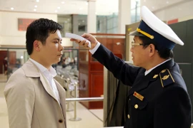 Cán bộ kiểm dịch Y tế cửa khẩu Hữu Nghị kiểm tra thân nhiệt của khách nhập cảnh bằng máy test nhanh. (Ảnh: Thái Thuần/TTXVN)