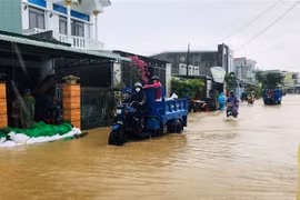 Lực lượng chức năng huyện Tuy Phước vận chuyển cát giúp người dân đắp bờ nước lũ tràn vào nhà. (Ảnh: TTXVN phát)