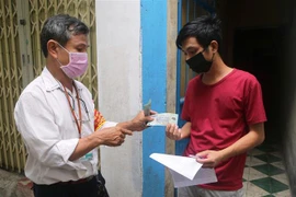 Ông Bùi Hữu Tài, Tổ trưởng dân phố 28 khu dân cư Xuân Đán 5 phát tiền hỗ trợ cho người dân tại Đà Nẵng. (Ảnh: Trần Lê Lâm/TTXVN)