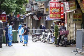 Lực lượng công nhân vệ sinh thu dọn rác thải tại khu vực phong tỏa phường Phú Đô, quận Nam Từ Liêm (Hà Nội). (Ảnh: Tuấn Đức/TTXVN)