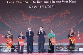 Chủ tịch Quốc hội Vương Đình Huệ và Chủ tịch Ủy ban Trung ương Mặt trận Tổ quốc Việt Nam Đỗ Văn Chiến trao quà cho các đại biểu dân tộc tại Làng Văn hóa. (Ảnh: Doãn Tấn/TTXVN)