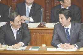 Thủ tướng Nhật Bản Shinzo Abe (P) trao đổi với Chánh Văn phòng Nội các Yoshihide Suga trong phiên họp tại Hạ viện. (Ảnh: Kyodo)