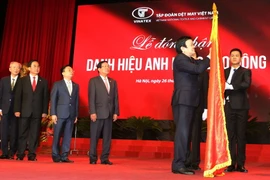 Chủ tịch nước Trương Tấn Sang gắn danh hiệu Anh hùng Lao động lên lá cờ truyền thống của Tập đoàn Dệt may Việt Nam. (Ảnh: Nguyễn Khang/TTXVN) 