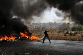 Thanh niên Palestine ném đá trong cuộc đụng độ với lực lượng an ninh Israel tại Al-Bireh, Bờ Tây ngày 26/10. (Nguồn: AFP/TTXVN)