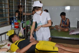 Bác sỹ của Trung tâm y tế quận Liên Chiểu điều trị cho bệnh nhân sốt xuất huyết. (Ảnh: Đinh Văn Nhiều/TTXVN)