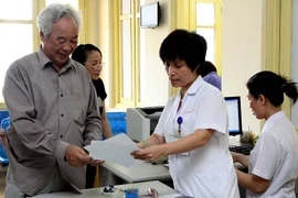 Nhân viên y tế Bệnh viện Bạch Mai hướng dẫn người khám chữa bệnh giải quyết thủ tục. (Ảnh: Dương Ngọc/TTXVN)