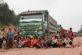 Nhiều người trải chiếu, ngồi canh không cho xe qua lại công trình. (Ảnh: Quang Duy/TTXVN)